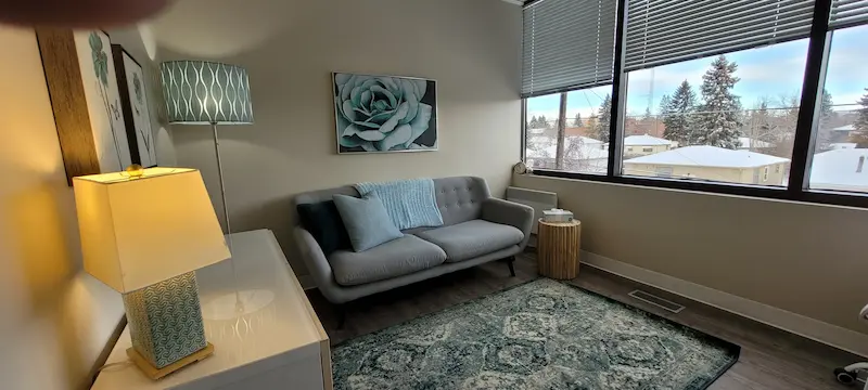 Spacious therapy office with a comfortable couch and large window overlooking NW Calgary.